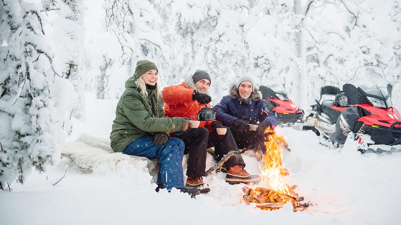 Group sitting by a campfire in snowy forest
